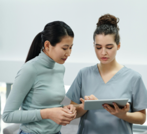 Training care staff 101. Two healthcare professionals are focused on a tablet, sharing insights and information.