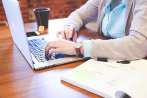 Ensuring compliance in agency care. Female hands on a laptop, sitting at a desk